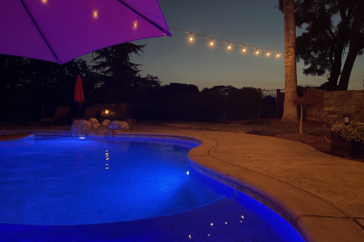 Freeform pool with string lights at dusk